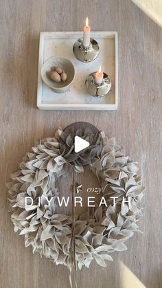 a wreath sitting on top of a wooden table next to two candles and a tray