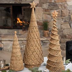 three wicker christmas trees sitting on top of a table next to a fire place