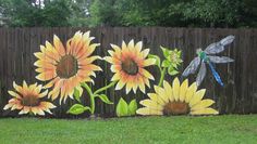 a painting of sunflowers and dragonflies on a fence