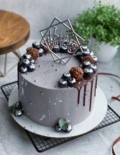 a birthday cake with chocolate frosting and decorations on top is sitting on a cooling rack