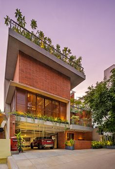 a car is parked in front of a building with plants on the roof and balconies above it