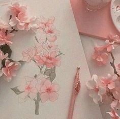 pink flowers are on the table next to a pen and paper