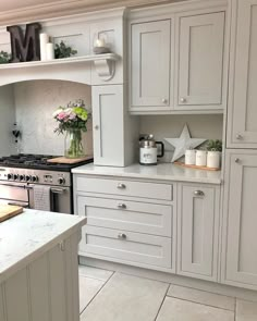 a kitchen with white cabinets and marble counter tops