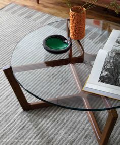 a glass table with a book on it and a potted plant in the middle