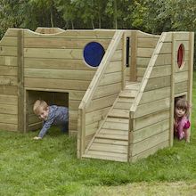 two children are playing in a wooden play house with stairs and ladders on the grass