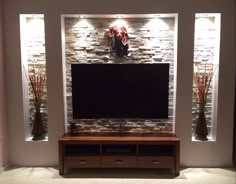 a flat screen tv mounted to the side of a stone wall in a living room