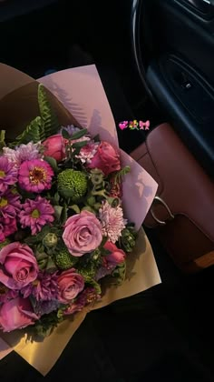 a bouquet of flowers sitting on top of a piece of paper next to a car door