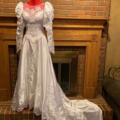 a white wedding dress is on display in front of a fire place with a fireplace