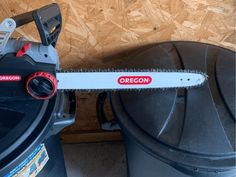 a black trash can with a red oregon sign on it next to a white and gray cordless chainsaw