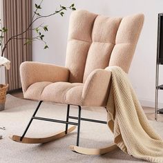 a rocking chair with a blanket on it in front of a tv and a plant