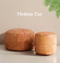 two leather stools sitting next to each other on a white surface with the words medium tan above them