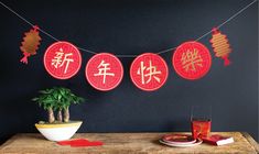 red paper lanterns are hung on a string above a table with a potted plant