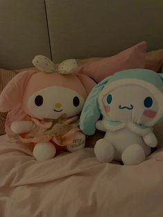 two stuffed animals sitting on top of a bed