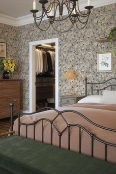 a bed room with a neatly made bed and a chandelier hanging from the ceiling