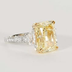 a fancy yellow diamond ring with diamonds around the band and an oval cut center stone