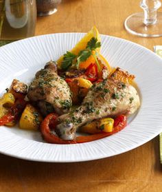 a white plate topped with chicken and veggies on top of a wooden table