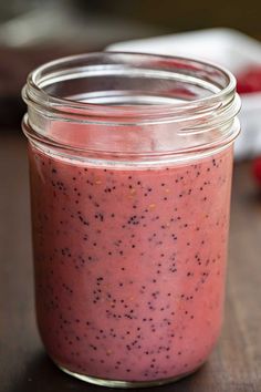 a glass jar filled with pink smoothie sitting on top of a wooden table