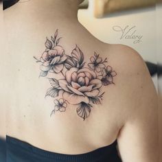 a woman with a flower tattoo on her back and shoulder, looking at the camera