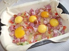 three eggs are on top of ham and onions in a skillet with parchment paper