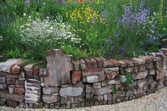 a stone wall surrounded by flowers and plants