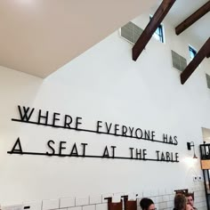 two people sitting at a table in front of a sign that says where everyone has a seat at the table