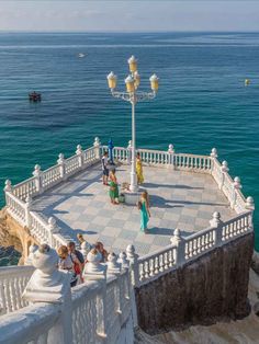 people standing on the edge of a pier next to the ocean