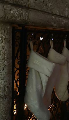 two white stockings hanging from a wrought iron gate in front of a fireplace at night