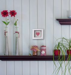 three vases filled with flowers sitting on top of a shelf