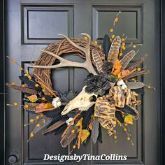 a wreath with antlers, feathers and leaves on it is hanging on the front door