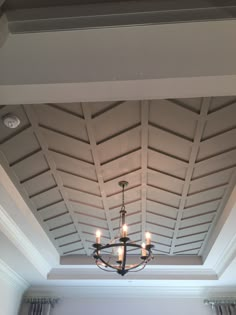 a chandelier hanging from the ceiling in a room with white walls and windows