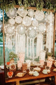 a table topped with lots of plates and desserts next to a wall covered in hanging lights