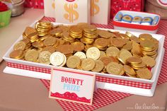 a table topped with lots of gold coins next to boxes filled with candy and other items