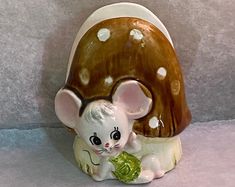 a ceramic mouse figurine sitting next to a mushroom