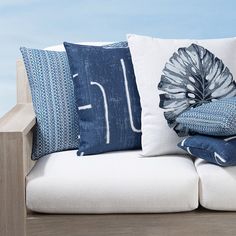 pillows are stacked on top of each other on a white couch with blue and gray accents