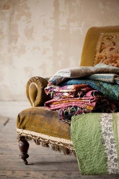 a pile of blankets sitting on top of an old chair