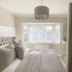 a bedroom with a bed, dresser and window in the corner that has shutters on both sides