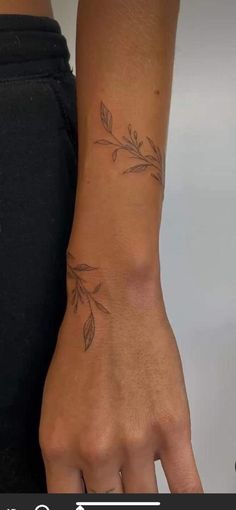 a woman's hand with a small branch tattoo on the left side of her arm