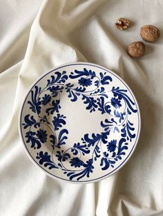 a blue and white plate sitting on top of a bed next to some walnuts