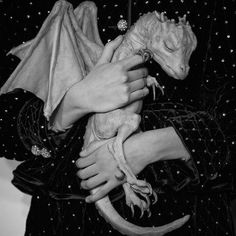 a black and white photo of a woman holding a dragon