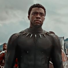 the black panther is standing in front of some other men with armor on their shoulders