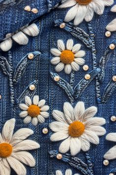 the back side of a jean jacket with white daisies on it and yellow centers