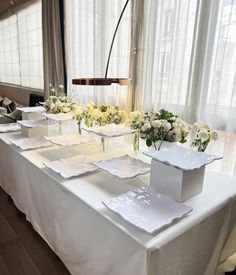 the table is set up with white flowers and place settings for guests to sit at