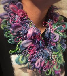 the woman is wearing a multicolored scarf with beads on her neck and black shirt