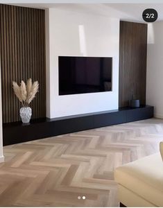 a living room with a large flat screen tv on the wall and wooden flooring