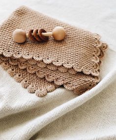 a crocheted bag with wooden buttons on it sitting on top of a white blanket