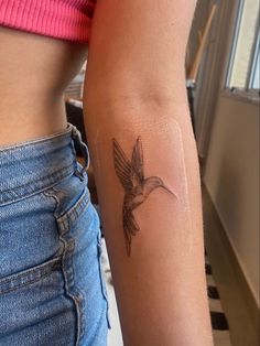 a woman's arm with a small tattoo of a hummingbird on the side