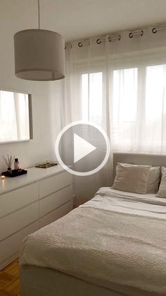 a white bed sitting in a bedroom next to a window with curtains on the windowsill