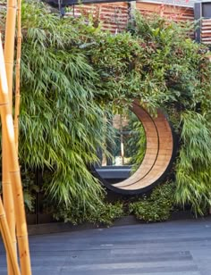 an outdoor fountain surrounded by greenery in front of a brick wall and wooden planters