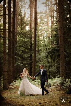 a bride and groom holding hands in the woods