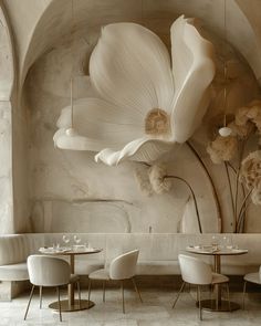 the interior of a restaurant with white chairs and flowers hanging from the ceiling over tables